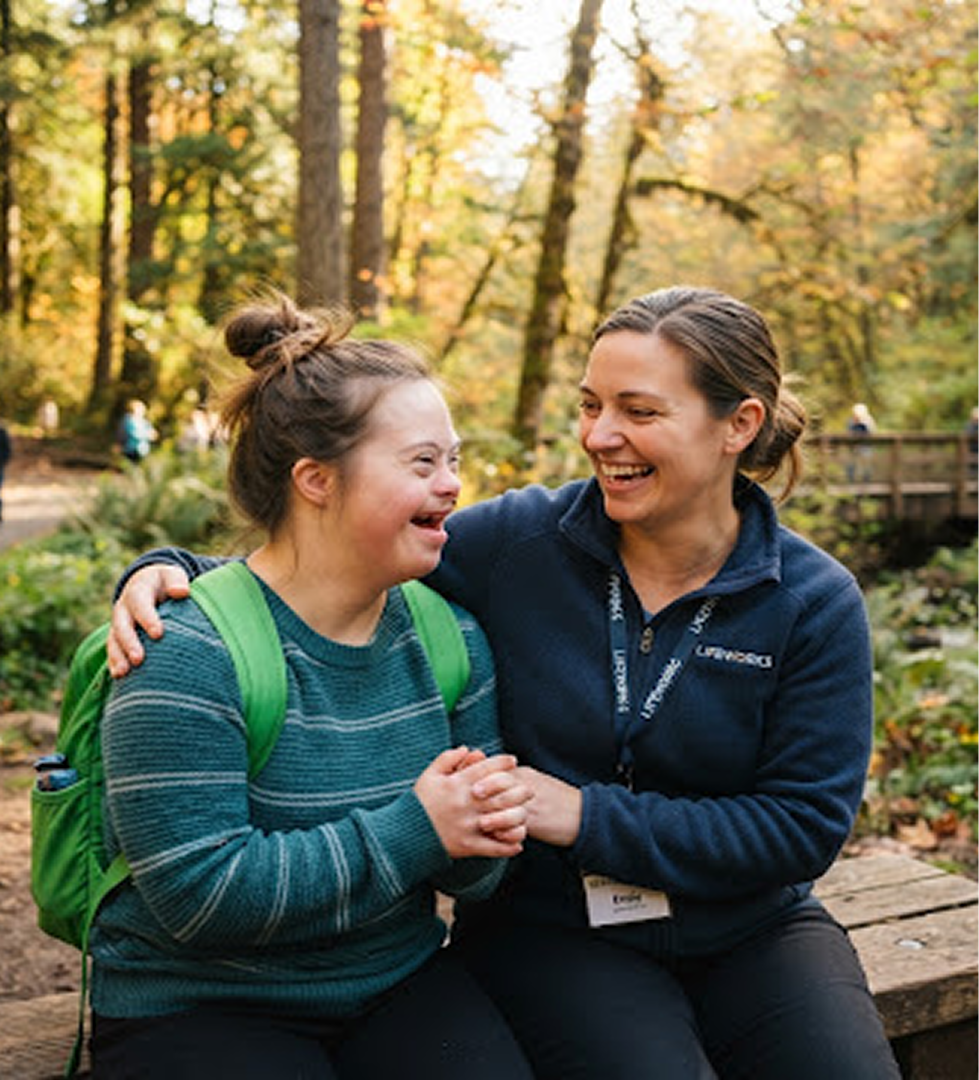 A PPFI support professional and a young woman laughing together on a forest trail